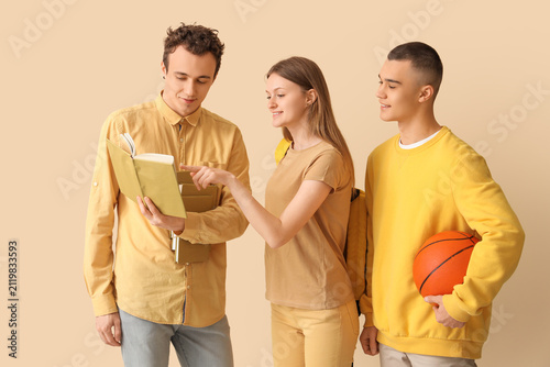 Group of students with books and ball on pale yellow background