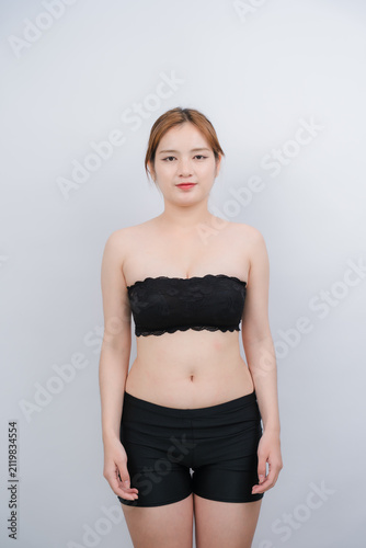 Young Woman in Activewear: A confident young woman posing in a comfortable black top and shorts, radiating natural beauty and physical wellness in a minimalist setting.