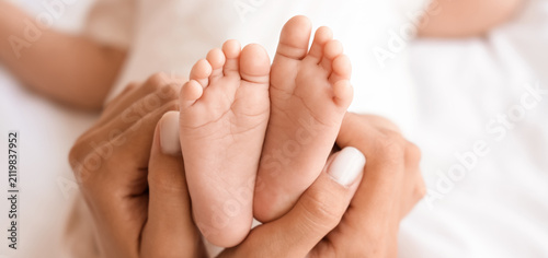 Obraz na płótnie Mother's hands gently holding tiny newborn baby feet, family love and care, New