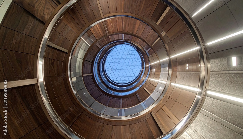 Fototapeta premium Modern Circular Wooden Staircase With Glass Atrium Ceiling Looking Upward