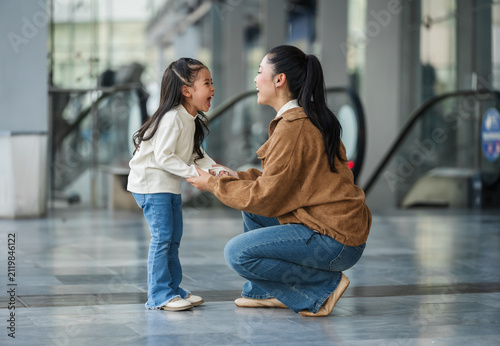 excited child girl laughing with her mother in shopping mall or department store