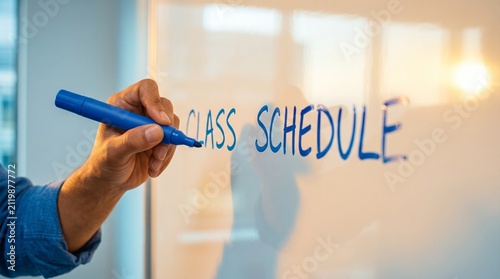 A hand writing on a transparent glass whiteboard with class schedule, suitable for modern education and university planning concepts.