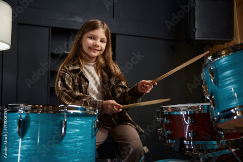 Foto Confident young girl executes drum performance amid vibrant lighting and colors