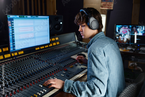 Sound engineer carefully calibrating sound levels in dimly lit studio