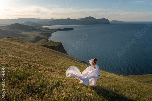 Bild auf Leinwand Woman dress mountain, a woman in a long white dress stands on a grassy hill over