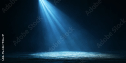 A single blue spotlight illuminates a textured surface in a dark, atmospheric setting, creating dramatic rays of light that pierce through the air, evoking a sense of mystery and focus.