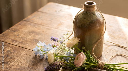 Bottle, flowers, and twine on rustic wood
