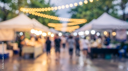 Abstract blurred night market scene with glowing golden bokeh lights and silhouettes of people walking past vendor booths under string lighting at an outdoor event