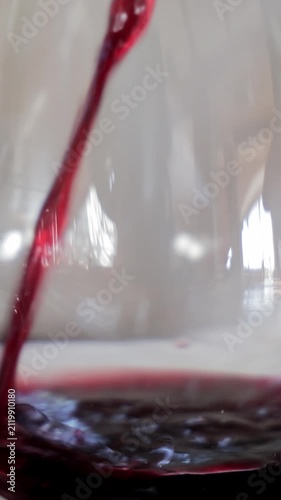 Red Wine Swirling in a Crystal Glass, Close-up of red wine being poured and swirling in a glass, highlighting the beverage's vibrant color and fluid motion.