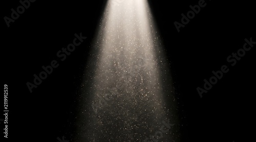 A single beam of light illuminates a cloud of shimmering particles against a dark background, creating a magical and ethereal atmosphere