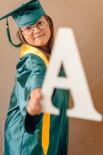 Konstfotografi Girl with down syndrome graduating showing letter a