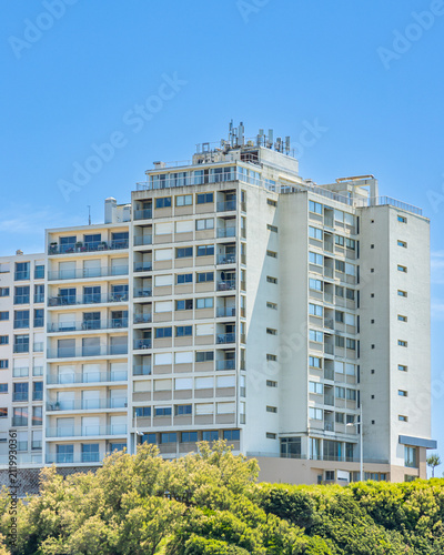High-rise concrete residential building standing above green coastal headlands in Biarritz, France