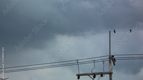The image features a cloudy, overcast sky with dark, ominous clouds dominating the background
