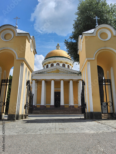 Exterior facade of Transfiguration Cathedral in classicism style with white columns and golden dome under blue sky in Dnipro, Ukraine.