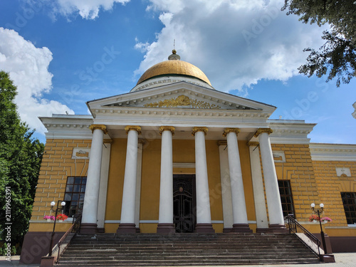 Exterior facade of Transfiguration Cathedral in classicism style with white columns and golden dome under blue sky in Dnipro, Ukraine.