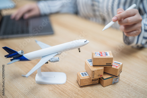 Business professional planning global air cargo shipping with airplane model and parcel boxes in a modern workspace. E-commerce logistics