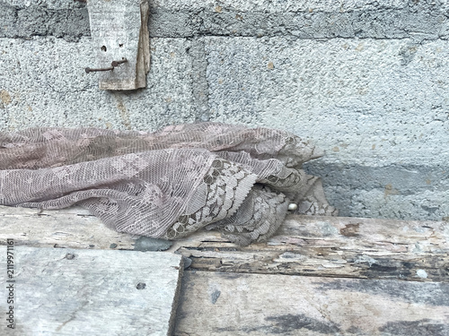 Old discarded piece of fabric lying on rough stone ground.
