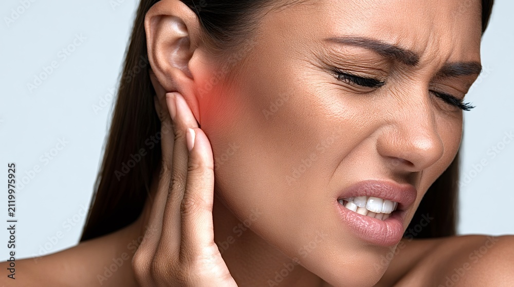 Obraz premium Woman feeling severe ear pain, touching her sore ear with a grimace, depicting health issues, otitis, and the discomfort of an infection