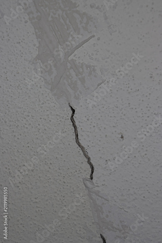 Textured Concrete Wall With Visible Crack and Surface Imperfections Partially Repaired with Filler or Putty