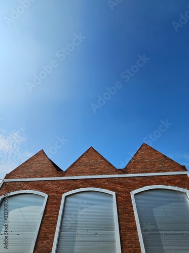 Obraz na plátně Minimalist industrial brick facade warehouse building with metal rolling shutter