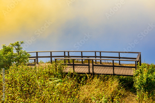 Landscape Series : Warm sunlight shines through drifting fog on the wooden boardwalk viewpoint deck at Kew Mae Pan Nature Trail in Chiang Mai Thailand.