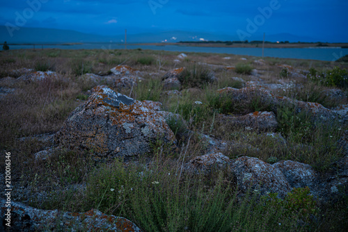 Mossy Boulders and Rocky Field at Dusk overlooking Lake in Twilight