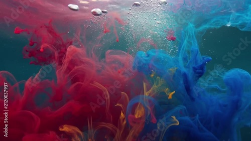Abstract red and blue ink diffusing and swirling under water with bubbles
