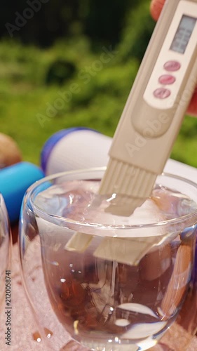 Vertical video. Person Comparing Water Samples With a Digital TDS Meter, Measuring Total Dissolved Solids to Detect Clean and Contaminated Drinking Water, Close Up, Water Safety