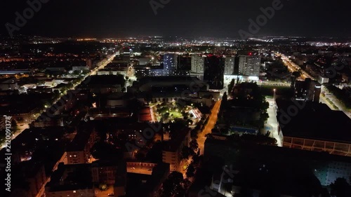 Night aerial footage of Bratislava, Slovakia, overlooking JAMA Park, the National Football Stadium and the Three Towers residential complex. The panoramic drone view captures illuminated streets