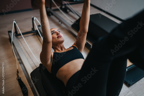 Foto Young woman performs a Pilates reformer exercise on a reformer machine