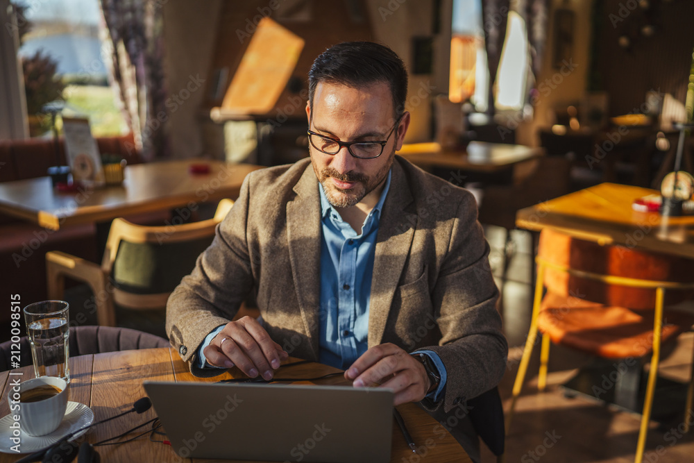 Obraz premium Man working remotely at cafe using laptop
