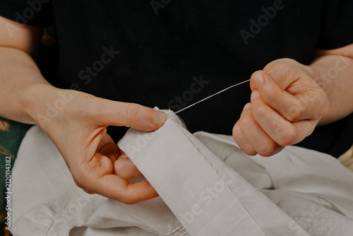 Mujer cosiendo una tela blanca a mano con aguja e hilo