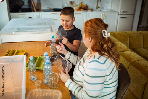 Mother and son sorting recyclables in home kitchen