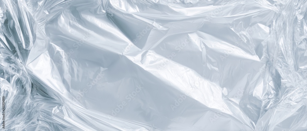 Obraz premium Ultra-minimalist background: crumpled clear plastic sheet, shiny surface, reflective