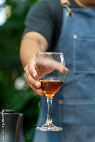 Barista presenting a carefully brewed Panama Geisha filter coffee in a wine glass, focusing on its complex aroma and delicate sensory experience at an outdoor cafe - stock photo
