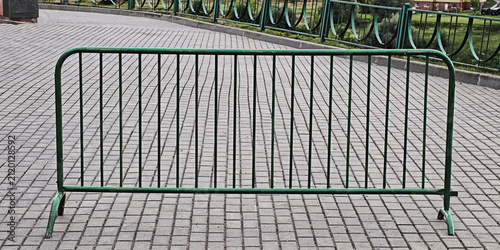 Fotografía Temporary green metal barrier standing on a textured paved surface, establishing
