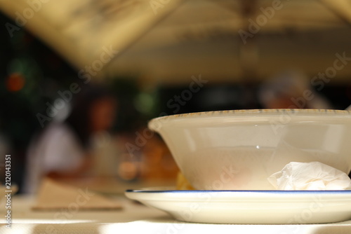 White soup plate and blurred colorful background.