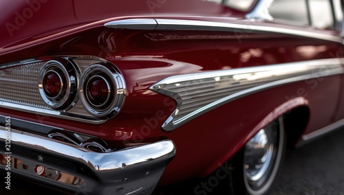 Close-up side view of an old red car's rear.