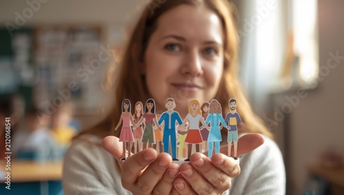 Closeup of a woman holding paper cutouts of people, representing inclusion.