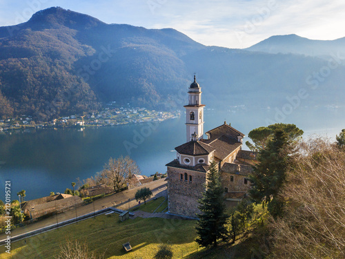 Aerial image of the parish church SS. Fedele e Simone istands on the high hill of Vico Morcote. Morcote at the Lake Lugano was once credited as one of the most beautiful Swiss villages.