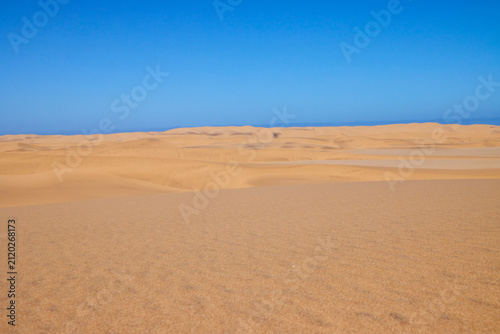 Eine glatte Sandfläche liegt vor sanften Dünen in der Wüste bei Swakopmund in der Region Erongo, Namibia.
