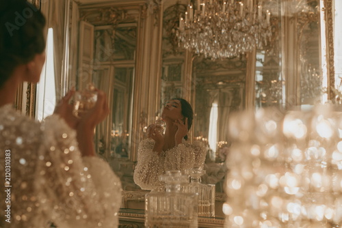 Elegant woman standing before a mirror in a luxurious classic interior, celebrating beauty rituals, fragrance, sophistication and timeless style.