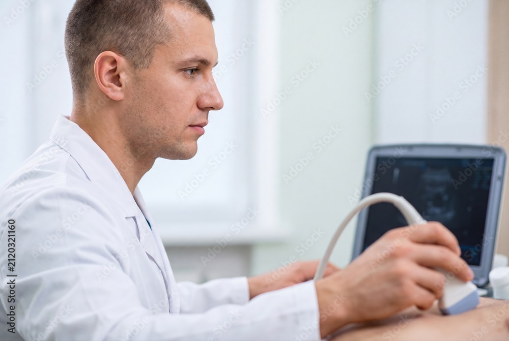 Fototapeta premium Male doctor performing ultrasound examination in modern medical clinic