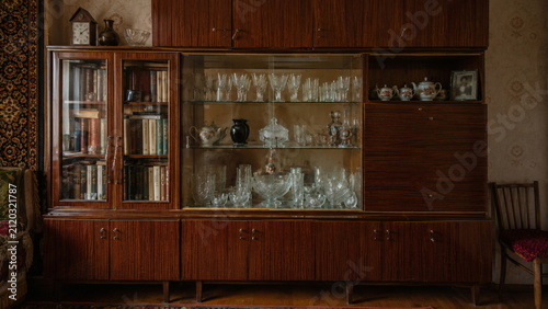 Vintage Soviet wooden display cabinet filled with crystal glassware and retro home décor, capturing nostalgic Eastern European interior design and history.