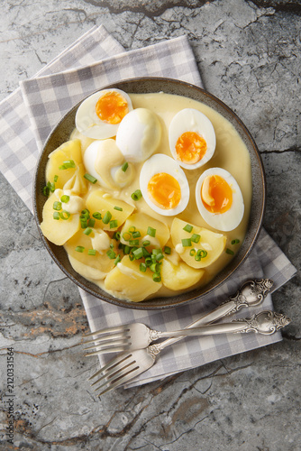 Senfeier or mustard eggs is a traditional German egg dish with a creamy mustard sauce and hard-boiled eggs close-up in a plate on the table. Vertical top view from above