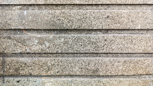 Sturdy grey granite or stone tiles accented with horizontal grooves captures the fine granular details, subtle color variations of the material for architectural design reference, construction texture