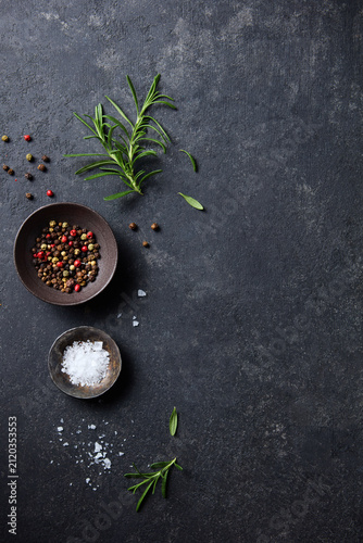 Food background with seasoning ingredients and fresh organic rosemary on black slate board. Dark background. Copy space. Top view.