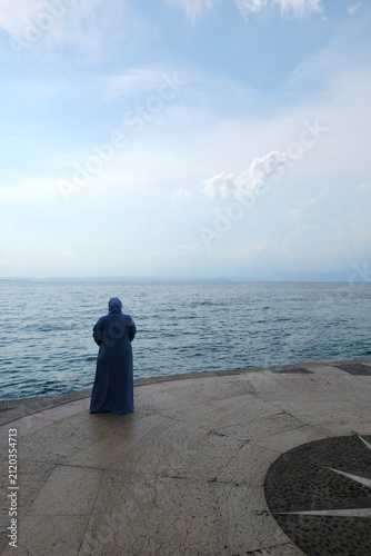 Person standing by the shore of Lake Garda at sunset, Sirmione, Italy
