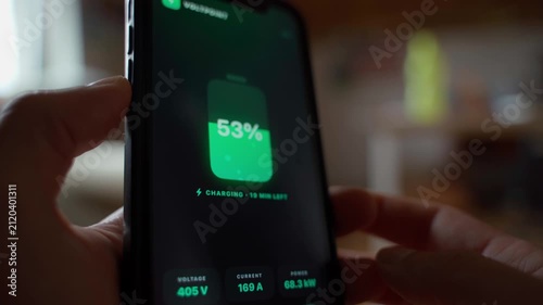 Hand holding smartphone showing battery charging app with power statistics close-up 