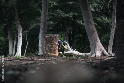 Player with paintball gun standing in the forest